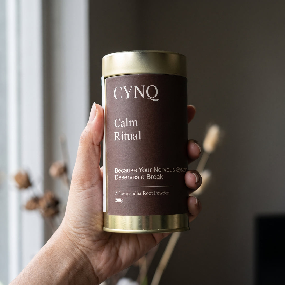 Hand holding a Calm Ritual ashwagandha powder tin with the label facing the camera