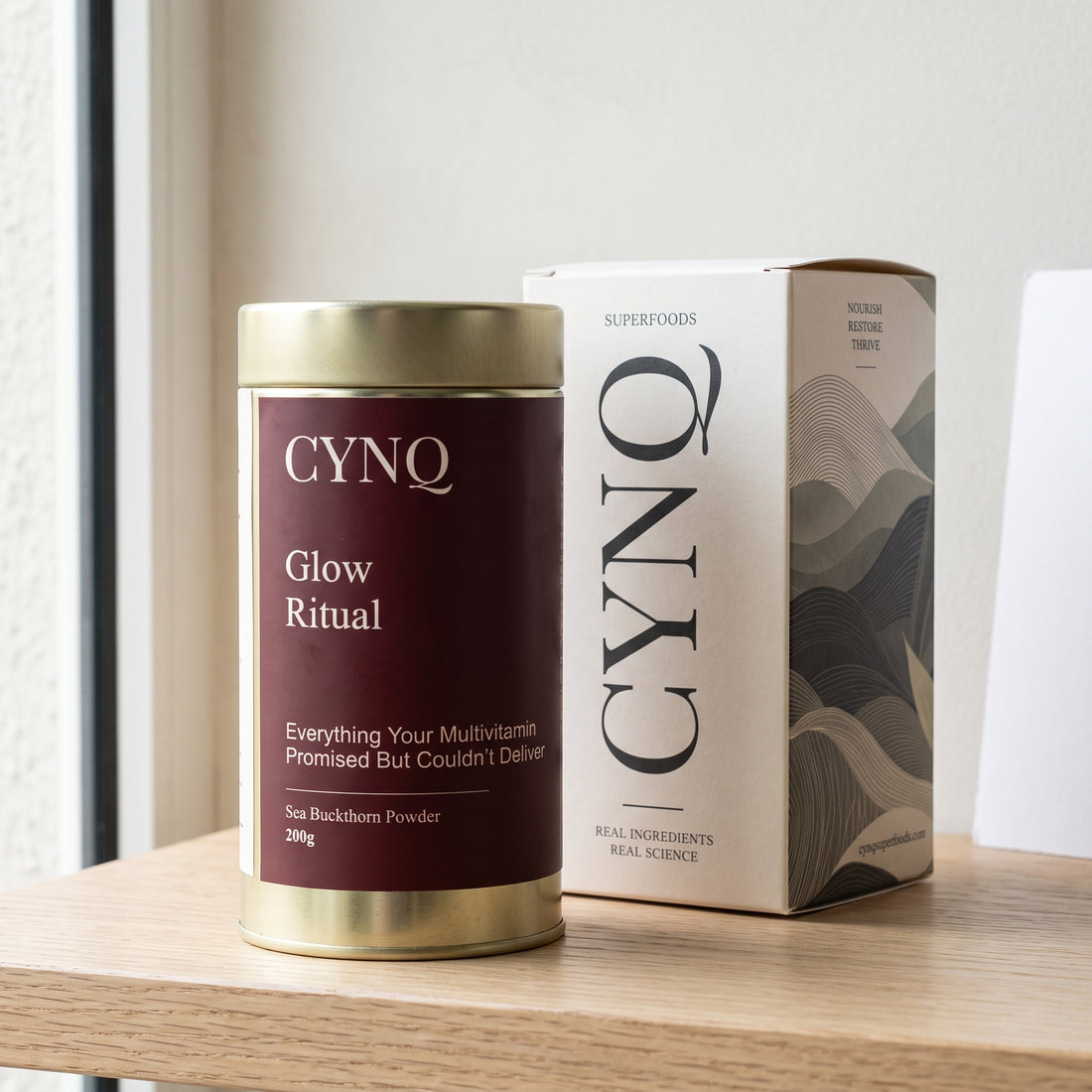 Glow Ritual sea buckthorn powder tin beside the CYNQ outer box on an oak shelf