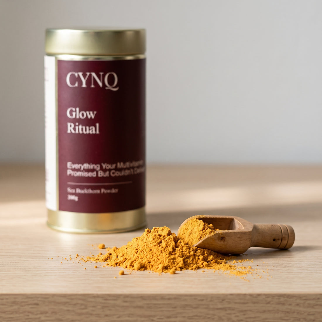 Orange sea buckthorn berry powder with a wooden scoop and a blurred Glow Ritual tin behind
