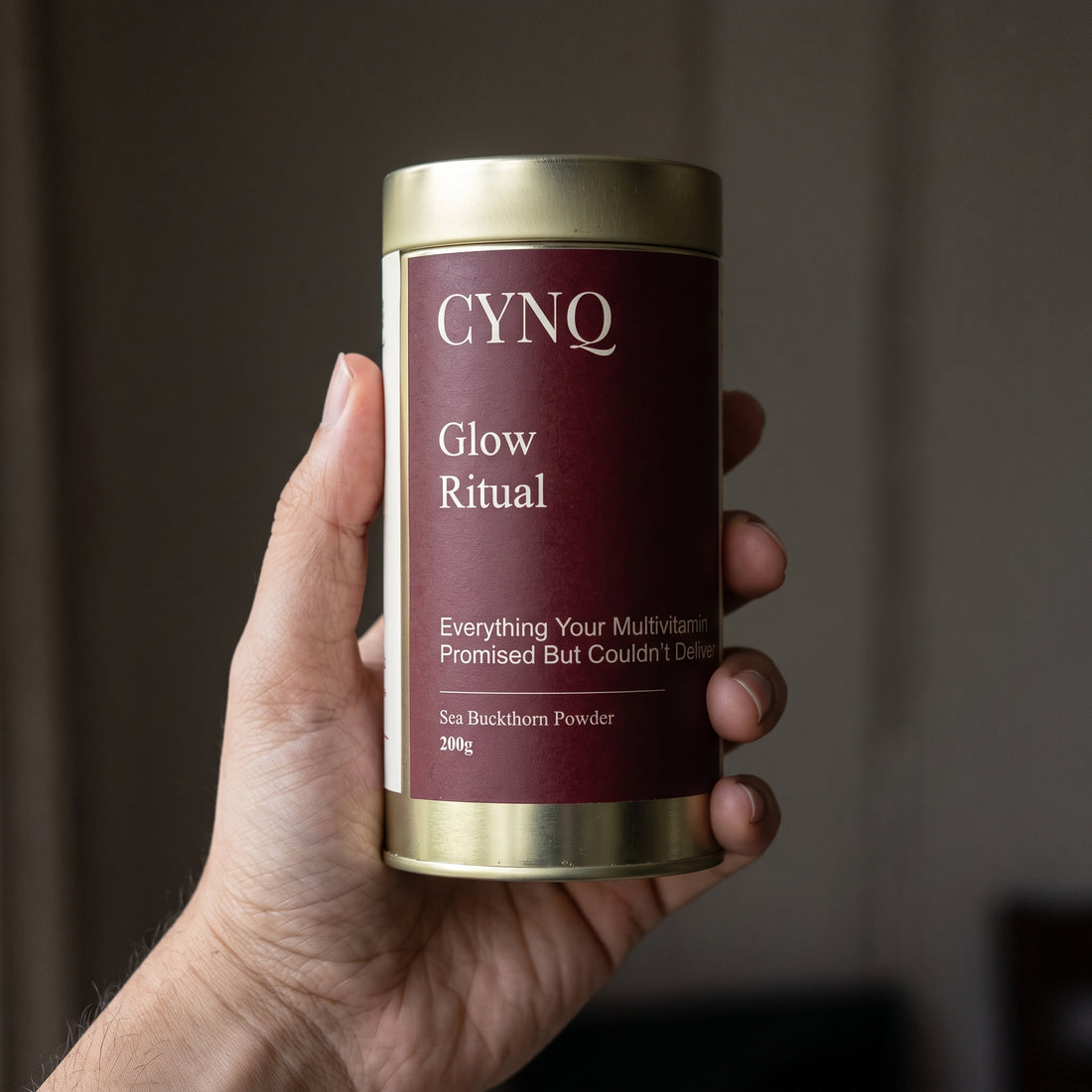Hand holding a Glow Ritual sea buckthorn powder tin with the label facing the camera