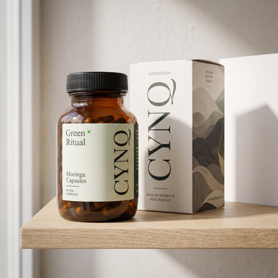Green Ritual capsule bottle beside the CYNQ outer box on a light oak shelf