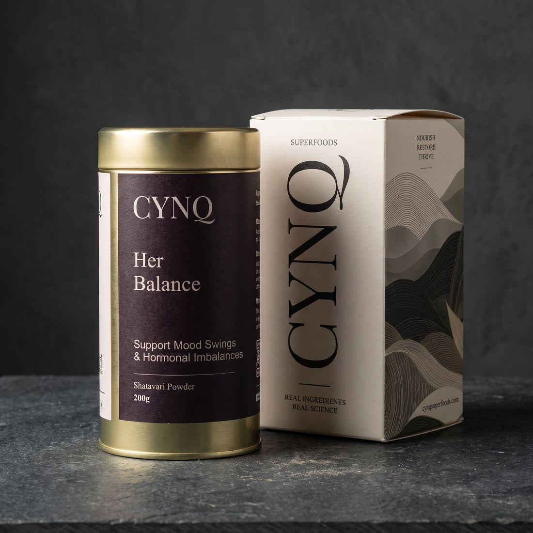 Her Balance shatavari powder tin beside the CYNQ outer box on dark slate