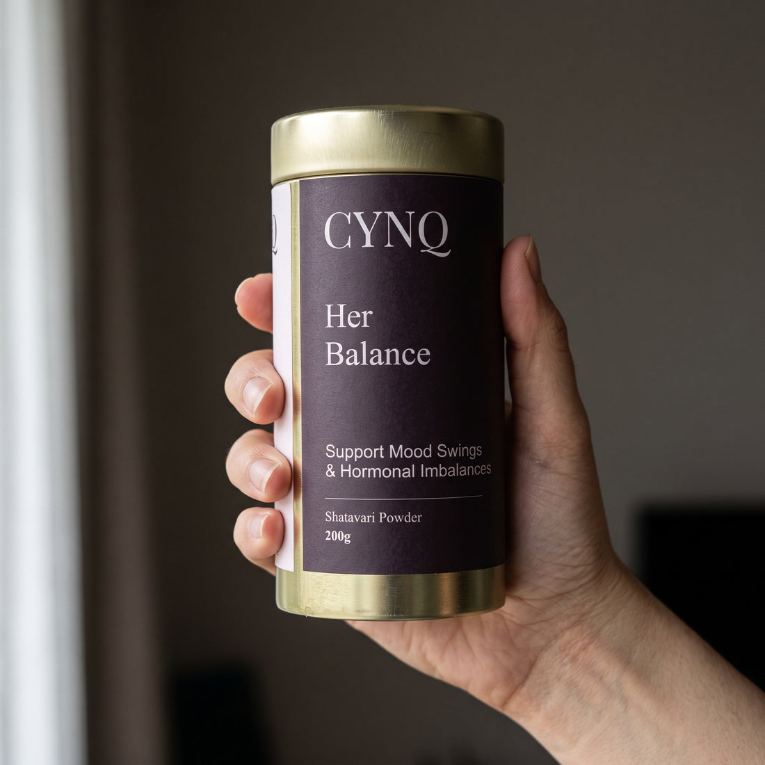 Hand holding a Her Balance shatavari powder tin with the label facing the camera