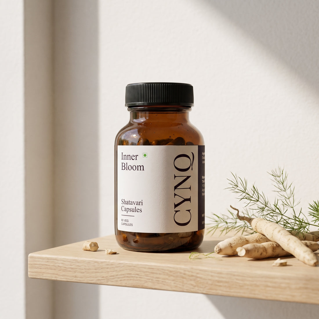 Inner Bloom capsule bottle on an oak shelf with fresh shatavari roots and a green sprig
