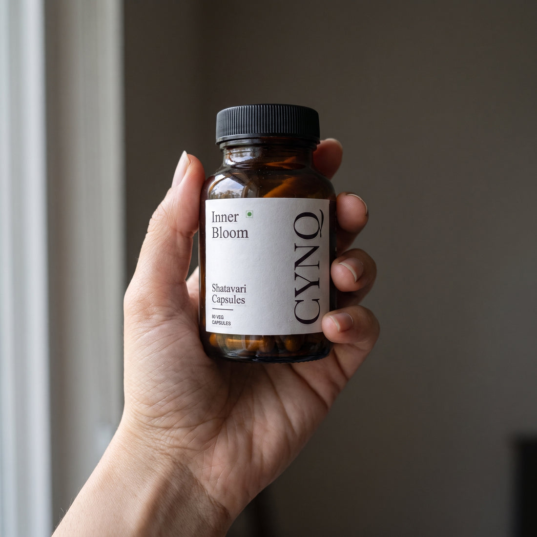 Hand holding an Inner Bloom shatavari capsule bottle with the label facing the camera