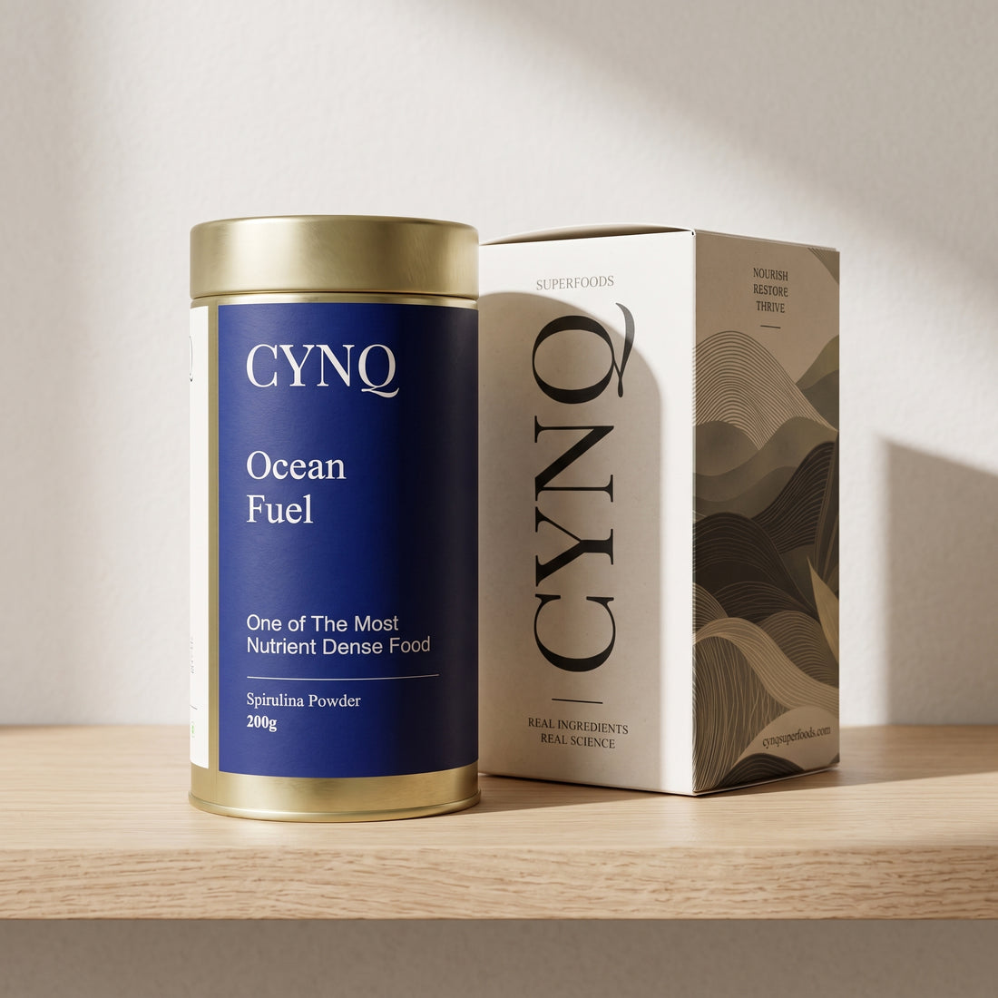 Ocean Fuel spirulina tin beside the CYNQ outer box on an oak shelf
