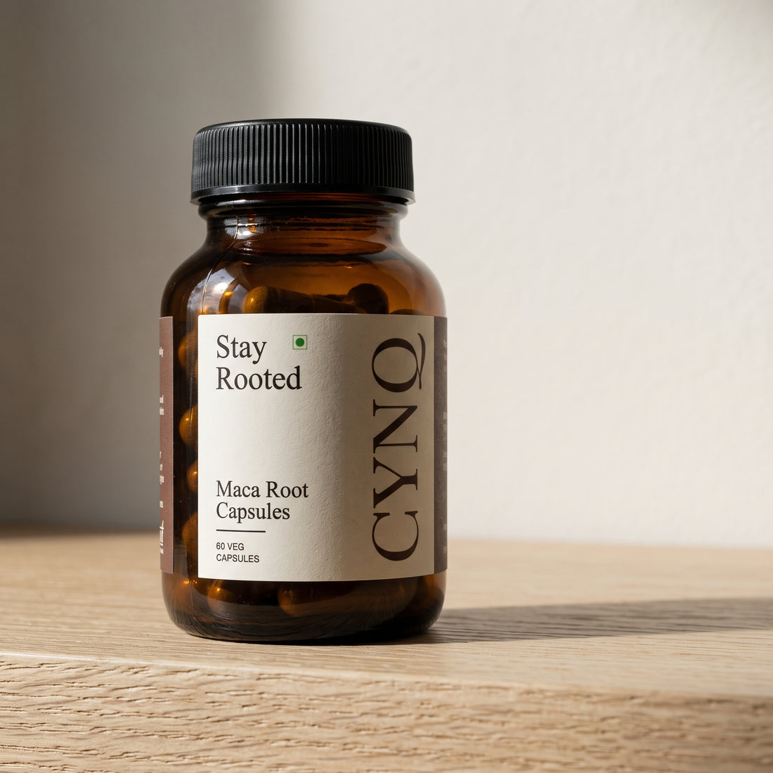 Stay Rooted maca capsule bottle, close front view, on an oak shelf against a pale wall