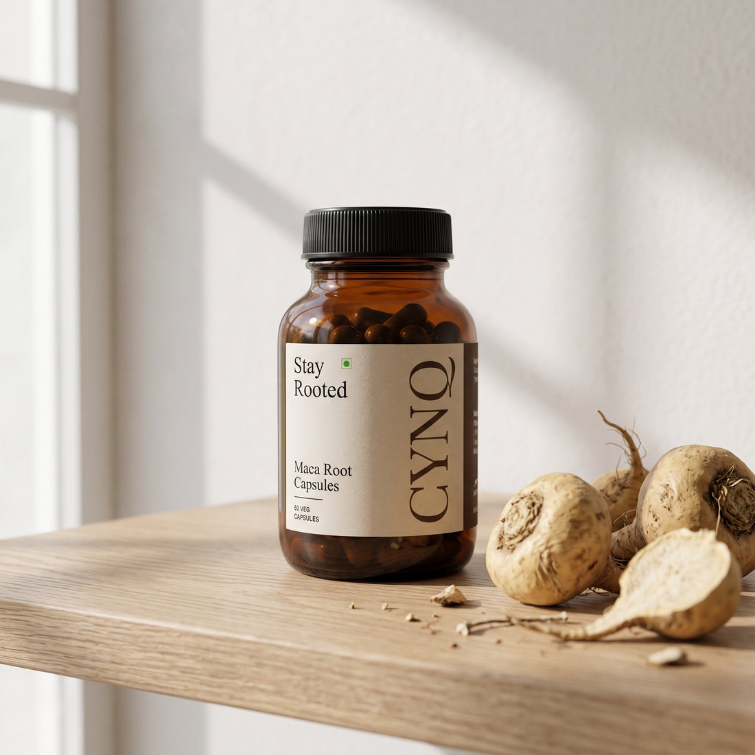 Stay Rooted capsule bottle on an oak shelf with whole maca roots